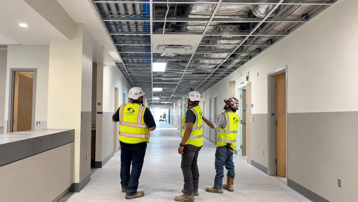 CCGroup Interiors crew reviewing ceiling grid in a hospital corridor